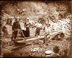 Three men and a woman working a sluice. 